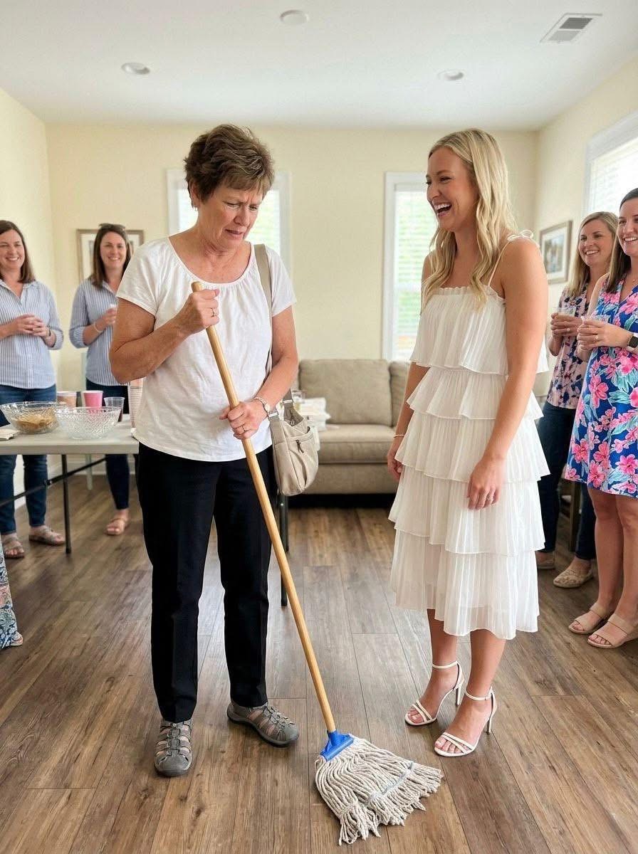 My future daughter-in-law handed me a mop in front of twenty guests at her bridal shower and told me to “earn my meal” — the gift I pulled from my purse made the entire room go completely silent.  I have one son. I raised him on my own after his father passed away.  I work as a janitor. It’s not glamorous, but it’s honest, steady work.  So when he told me he was getting married, I was truly happy for him.  Emily always seemed… polite. A little distant, maybe, but I told myself that’s just how some people are.  When I received the invitation to her bridal shower, I took it as a positive sign.  The event was held in a rented hall, decorated like something straight out of a magazine. Around twenty women, all perfectly dressed, holding drinks, laughing like they naturally belonged there.  I didn’t.  But I tried.  I greeted a few people, kept to myself, and waited for my son to arrive like he said he might.  Emily barely acknowledged me.  Then, halfway through the afternoon, she clapped her hands to get everyone’s attention.  “Before we eat,” she said sweetly, “let’s do something fun.”  A few guests laughed.  Moments later, she “accidentally” knocked over a full glass. It shattered across the floor, liquid spreading over the tiles.  Emily looked straight at me.  Then she picked up a mop and held it out.  “Since you didn’t really contribute much,” she added with a smile, “you can at least earn your meal. You should be used to this anyway.”  The room fell quiet.  Some women exchanged glances. Others looked away, pretending not to notice.  I felt the heat rise to my face.  But I didn’t argue.  I didn’t defend myself.  I simply reached into my purse…  (I know you’re curious about the next part, so please be patient and read on in the comments below. Thank you for your understanding of the inconvenience. please leave a ‘YES’ comment below and give us a “Like ” to get full story ) 👇